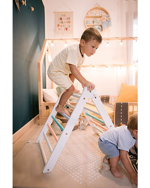 Due bambini si arrampicano sul triangolo Pikler Montessori Family Nation nella loro cameretta